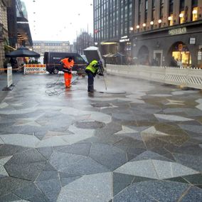 Työntekijät puhdistavat kävelykatua Helsingissä